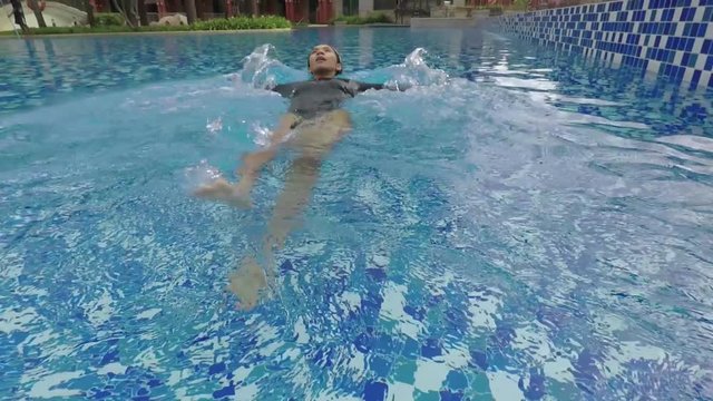 Video footage of happy young woman relaxing on a luxury hotel swimming pool while wearing swimsuit