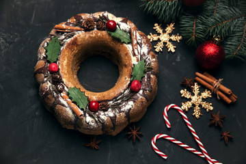 Traditional Christmas cake stollen decorated with white shugar powder and fruit festive wooden background