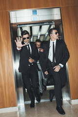 Bodyguard obstructing paparazzi when celebrity going out from elevator - obrazy, fototapety, plakaty