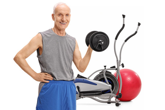 Senior exercising with a dumbbell in front of a cross training machine and a pilates ball