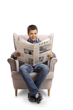 Young man sitting in an armchair and reading a newspaper