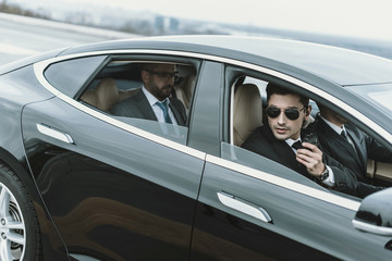bodyguards and businessman sitting in a black car