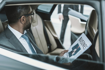 businessman sitting in a car and holding newspaper