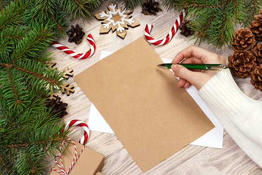 Famale Hand Writing A Christmas Letter On Wooden Background