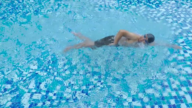 Video footage of a young male swimmer exercising in the swimming pool with blue water