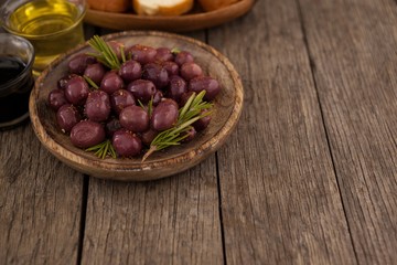 High angle view of olives with herb in wooden plate