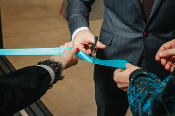 New business enterprise, opening, cutting a blue ribbon with scissors close-up.