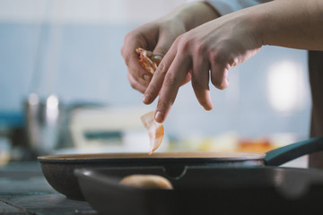 The chef fries bacon in a pan in the restaurant