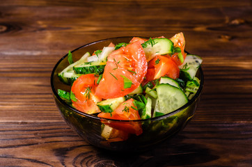Salad with cucumbers and tomatoes on wooden table