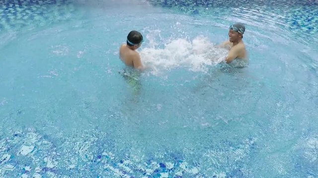 Video footage of a young father and his son enjoying holiday while swimming and playing water on the pool
