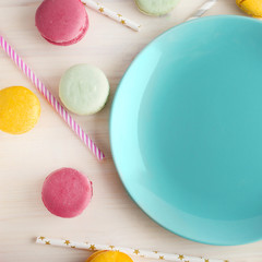 Empty bright blue plate, with a delicious dessert around, macaroons and tubes for a cocktail. Place for text. Festive layout, template.