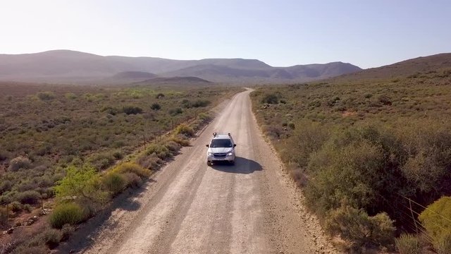 Aerial of car driving down long dirt road