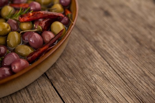 Cropped image of olives with oil and chili pepper in container