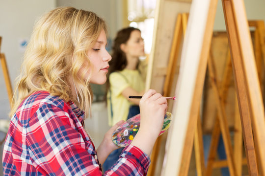 girl with easel painting at art school studio