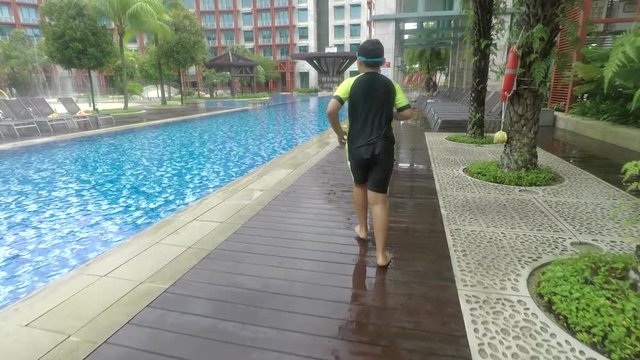 Video footage of a little boy running and jumping into the pool at the luxury hotel, shot outdoors
