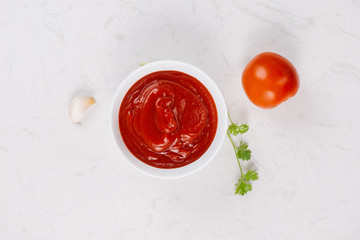 Bowl of ketchup and fresh tomatoes on table