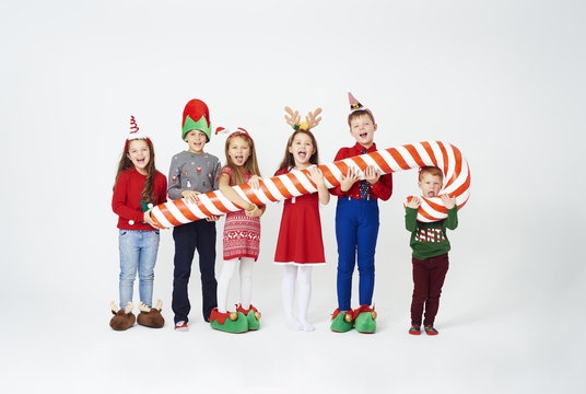 Happy children holding huge candy cane .