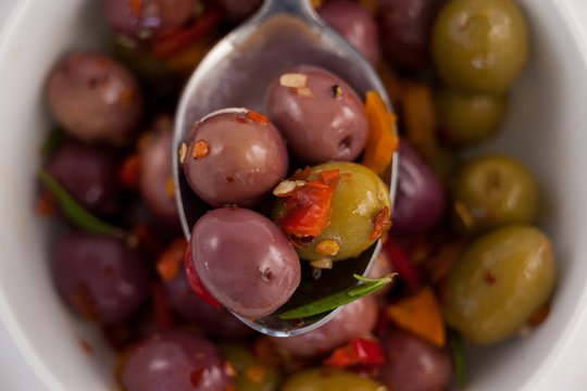 Close up of spoon with olives over container