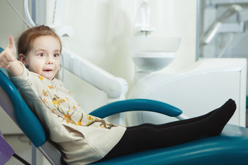 Little child sits in comfortable leather dentist chair
