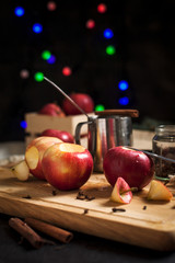 cooking of baked apples for New Year's holidays, Christmas tree and New Year's lights, honey and cinnamon on a wooden cutting board on a dark background