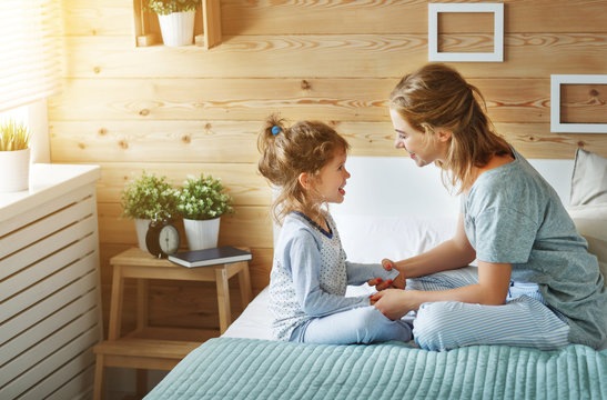 Happy Family Mother And Child Daughter Laughing In Bed