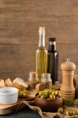 Fototapeta na wymiar Olives in bowl with oil bottles in background