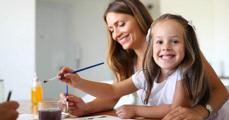 Little girl painting with her mother at home