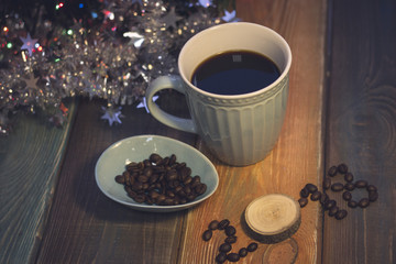 A romantic festive still life with a blue cup of freshly brewed coffee, a blue plate with coffee beans and 2018 inscription of coffee beans and a wooden circle. Colored wooden background.