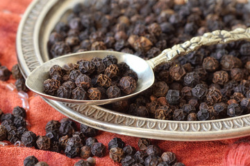 Black pepper on spoon and plate