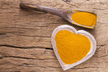 Turmeric powder with spoon on wood background (curcuma longa)