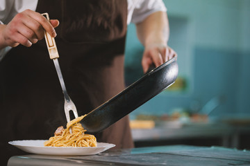 Chef serves spaghetti carbonara on the plate in restaurante