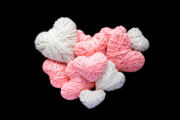 Big heart of small pink and white wool yarn heart shape isolated on black. Hearts of knitting threads background. Symbol of love. Hobby, love and romance concept
