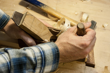 Hands of a craftsman on a old fashion woodworking plane