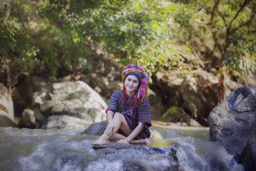 Fototapeta na wymiar Karen woman smile sit on the rock in stream