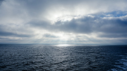 graue Wolken mit Lichtstrahlen über dem Meer