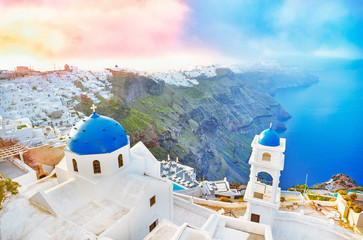 Greece, Santorini island in Aegean sea. Breathtaking dawn scenery with blue domed church on foreground and epic sunrise sky on background.