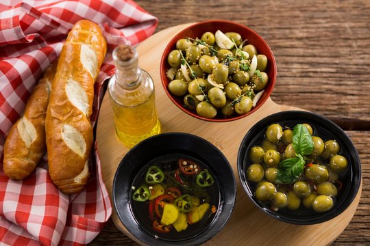 Marinated olives, bread and olive oil on heart shape board