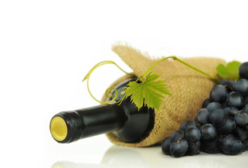 Grape leaf on the background of bottles of wine, black grapes and burlap. Place for inscription on white.
