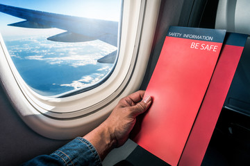 Asian man read flight safety instructions on card board flight. Blank safety instructions on board...