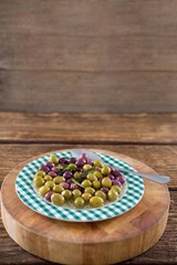 Obraz na płótnie Canvas Marinated olives with herbs on wooden board