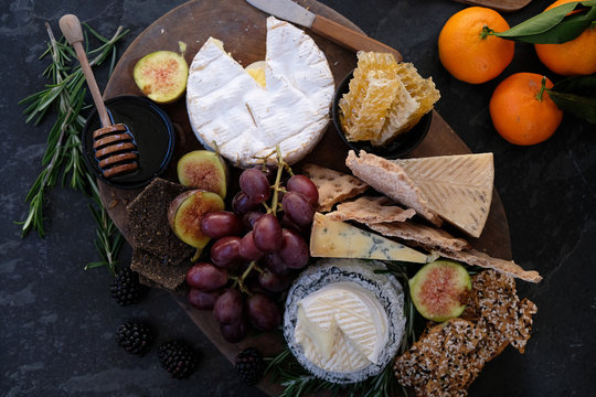 Seasonal cheese platter, with a variety of cheeses, fruit, honey, crackers and sprigs of rosemary. 