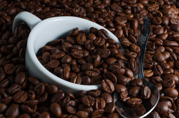 White Cup and a tea spoon drowned in coffee beans