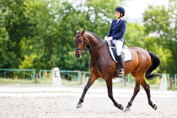 Young rider woman on her course in dressage competition advanced test