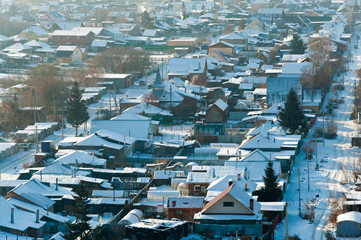 Fototapeta premium Rustic houses in winter, light smoke from the pipes. Top view with blur.