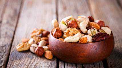 Naklejka na ściany i meble Nuts Mixed in a wooden plate.Assortment, Walnuts,Pecan,Almonds,Hazelnuts,Cashews,Pistachios.Concept of Healthy Eating.Vegetarian.Copy space.selective focus.