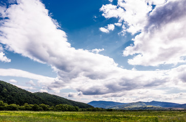 Fototapeta na wymiar agricultural fields in mountainous countryside. lovely landscape with gorgeous cloudy sky
