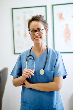 Portrait of professional happy nurse with stethoscope standing in the office and looking at the camera.