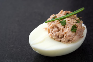 Stuffed eggs with tuna on black stone.Copyspace