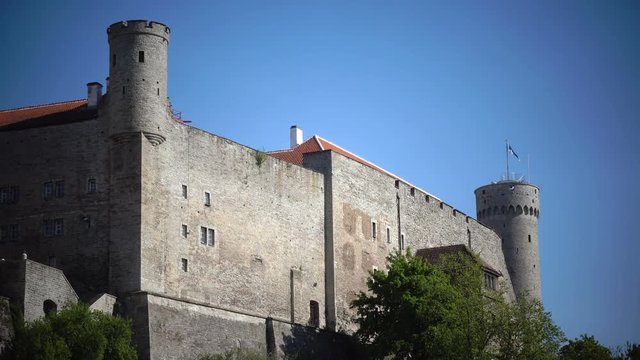 National flag of Estonia on blue sky move over Long Herman - a tower of Toompea Castle on the hill Toompea. Tallinn, Estonia