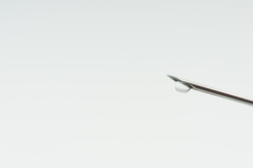 Medical needle, focus on the liquid drop isolated on white background.
